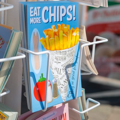 Brighton, UK - July 28, 2013: Eat more chips postcard in a postcard rack on the seafront in Brighton, July 2013.